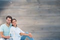 Composite image of cute couple sitting holding a house shape Royalty Free Stock Photo