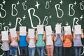 Composite image of cute pupils with funny faces in classroom