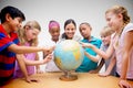 Composite image of cute pupils and teacher looking at globe in library Royalty Free Stock Photo