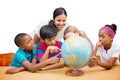 Composite image of cute pupils and teacher looking at globe in library Royalty Free Stock Photo