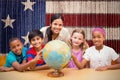 Composite image of cute pupils and teacher looking at globe in library Royalty Free Stock Photo