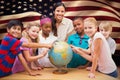 Composite image of cute pupils and teacher looking at globe in library Royalty Free Stock Photo