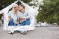 Composite image of cute young couple sitting on skateboard kissing