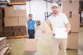 Composite image of delivery man with cardboard box showing clipboard Royalty Free Stock Photo