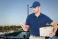 Composite image of delivery man using mobile phone while holding package Royalty Free Stock Photo