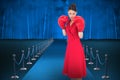 Composite image of elegant brunette in red dress wearing boxing gloves Royalty Free Stock Photo