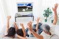 Composite image of family raising their arms in front of television Royalty Free Stock Photo