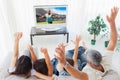 Composite image of family raising their arms in front of television Royalty Free Stock Photo