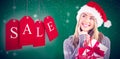 Composite image of festive blonde holding christmas gift and bag Royalty Free Stock Photo