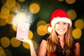 Composite image of festive blonde holding a gift bag Royalty Free Stock Photo