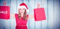 Composite image of festive blonde holding sale shopping bags Royalty Free Stock Photo