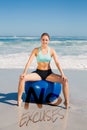 A Composite image of fit woman sitting on exercise ball at the beach Royalty Free Stock Photo