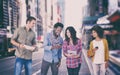 Composite image of four stylish friends looking at tablet and holding phones Royalty Free Stock Photo