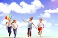 Composite image of full length of boy holding kite running with friends Royalty Free Stock Photo