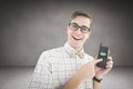 Composite image of geeky hipster holding a retro cellphone