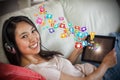 Composite image of girl using her tablet pc on the sofa and listening to music smiling at camera 3d Royalty Free Stock Photo