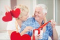 Composite image of hanging hearts and senior couple opening a gift box Royalty Free Stock Photo