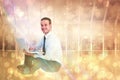 Composite image of happy businessman sitting and using laptop Royalty Free Stock Photo