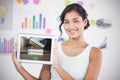 Composite image of happy businesswoman showing digital tablet in creative office Royalty Free Stock Photo