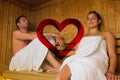 Composite image of happy couple relaxing in a sauna