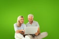 Composite image of happy couple sitting and using laptop Royalty Free Stock Photo