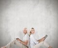 Composite image of happy couple sitting using laptop and tablet pc Royalty Free Stock Photo