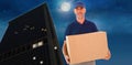 Composite image of happy delivery man holding cardboard box Royalty Free Stock Photo