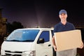 Composite image of happy delivery man holding cardboard box Royalty Free Stock Photo