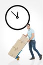 Composite image of happy delivery man pushing trolley of boxes Royalty Free Stock Photo