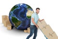 Composite image of happy delivery man pushing trolley of boxes Royalty Free Stock Photo