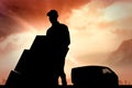 Composite image of happy delivery man pushing trolley of boxes Royalty Free Stock Photo