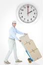 Composite image of happy delivery man pushing trolley of cardboard boxes Royalty Free Stock Photo