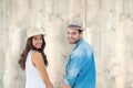 Composite image of happy hipster couple holding hands and smiling at camera Royalty Free Stock Photo