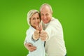 Composite image of happy mature couple showing thumbs up Royalty Free Stock Photo