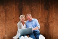 Composite image of happy mature couple using laptop Royalty Free Stock Photo