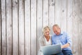 Composite image of happy mature couple using laptop Royalty Free Stock Photo