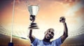 Composite image of happy sportsman looking up and cheering while holding trophy Royalty Free Stock Photo
