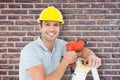 Composite image of happy technician holding drill machine while leaning on ladder Royalty Free Stock Photo