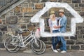 Composite image of hip young couple hugging by brick wall with their bikes