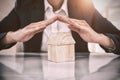 Composite image of insurer protecting a house by his hands