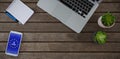 Composite image of laptop, pot plant, notepad, pen and mobile phone on wooden plank Royalty Free Stock Photo