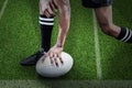 Composite image of low section of sportsman holding rugby ball