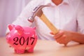 Composite image of man breaking piggy bank with hammer