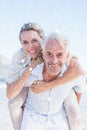 Composite image of man giving his smiling wife a piggy back at the beach Royalty Free Stock Photo