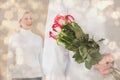 Composite image of man hiding bouquet of roses from older woman