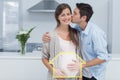 Composite image of man kissing his pregnant wife