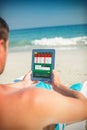 Composite image of man using digital tablet on deck chair at the beach Royalty Free Stock Photo