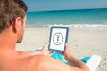 Composite image of man using digital tablet on deck chair at the beach Royalty Free Stock Photo