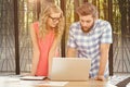 Composite image of man using laptop while discussing with woman at desk Royalty Free Stock Photo