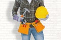 Composite image of manual worker wearing tool belt while holding hammer and helmet Royalty Free Stock Photo